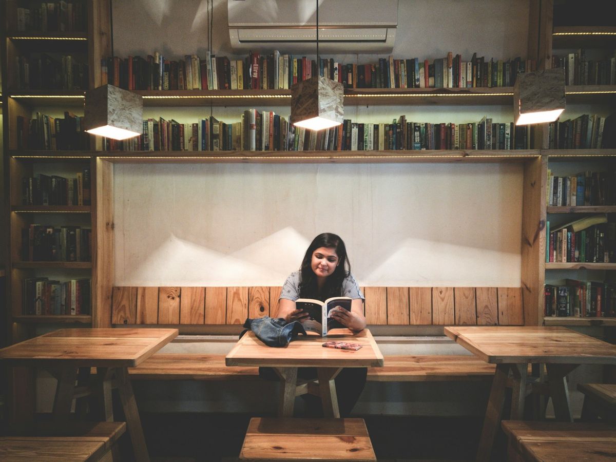 Student leser bok på biblioteket